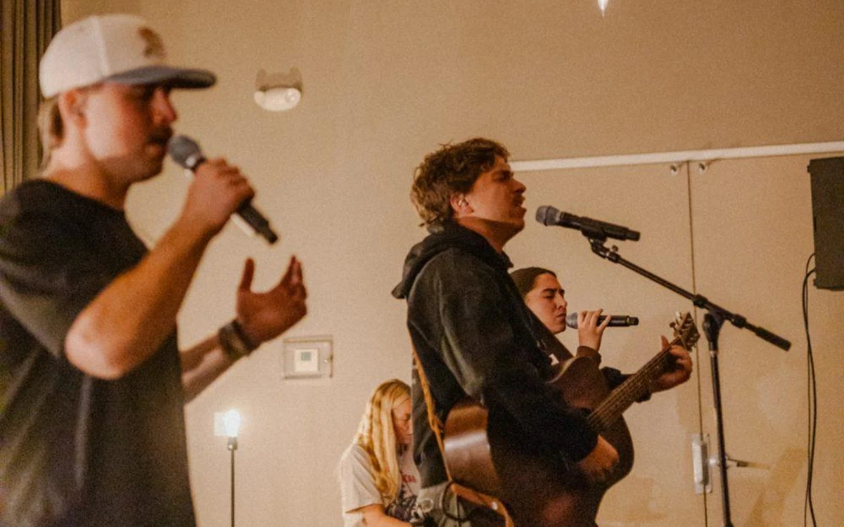 Noah singing and playing acoustic guitar while leading worship at Salt Company